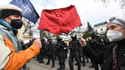 Demonstranti s rudými trenýrkami a policejní těžkooděnci před budovou velvyslanectví Ruské federace.