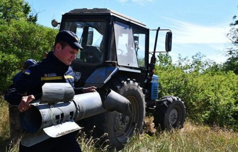 Příslušník Státní pohotovostní služby Ukrajiny odnáší  nevybuchlou ruskou bombu z pole na Ukrajině