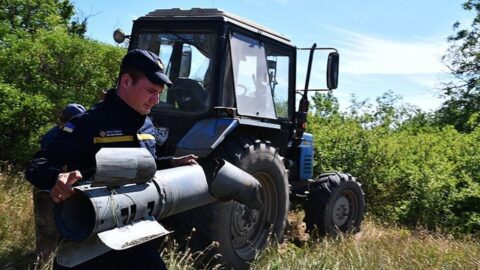 Příslušník Státní pohotovostní služby Ukrajiny odnáší  nevybuchlou ruskou bombu z pole na Ukrajině