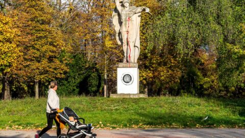 Žena prochází okolo sochy rudoarmějce potřísněné červenou barvou a s namalovanou pračkou na podstavci, 25. října 2022 v Jiráskových sadech v Litoměřicích.