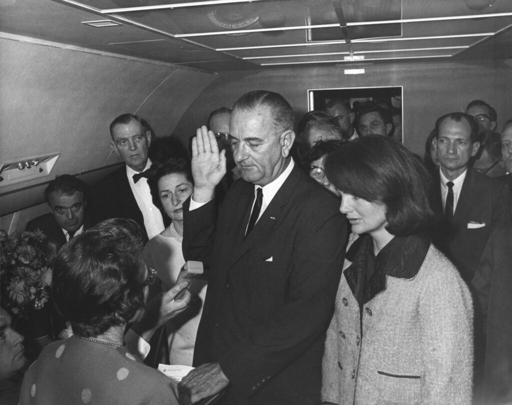 Lyndon B. Johnson skládá prezidentskou přísahu na palubě Air Force One. 