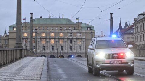 Vůz s majáky projíždí přes uzavřený Mánesův most od nám. Jana Palacha, kde se v budově Filozofické fakulty (v pozadí) střílelo.